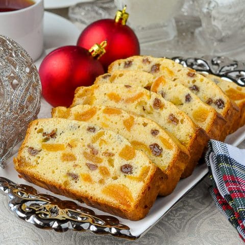 Aprivot raisin cake on a white and silver platter with red Christmas tree decorations.