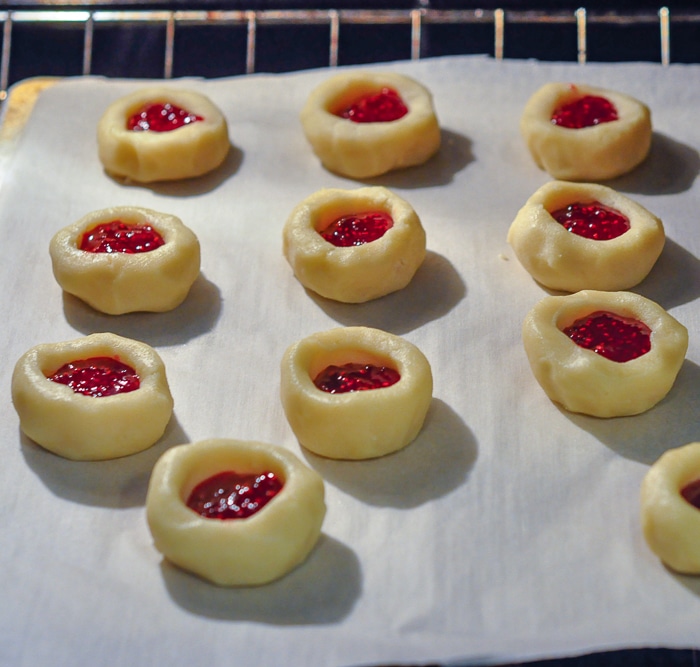 Raspberry Orange Thumbprint Cookies shown on a parchment paper lined baking sheet in the oven