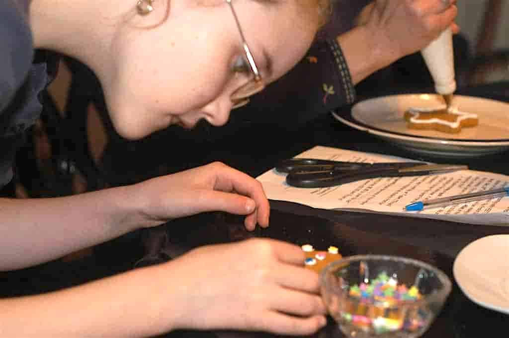 Olivia Close up adding decorations to cookies.