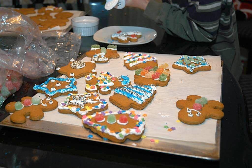 Kids decorating christmas gingerbread cookies on a table/