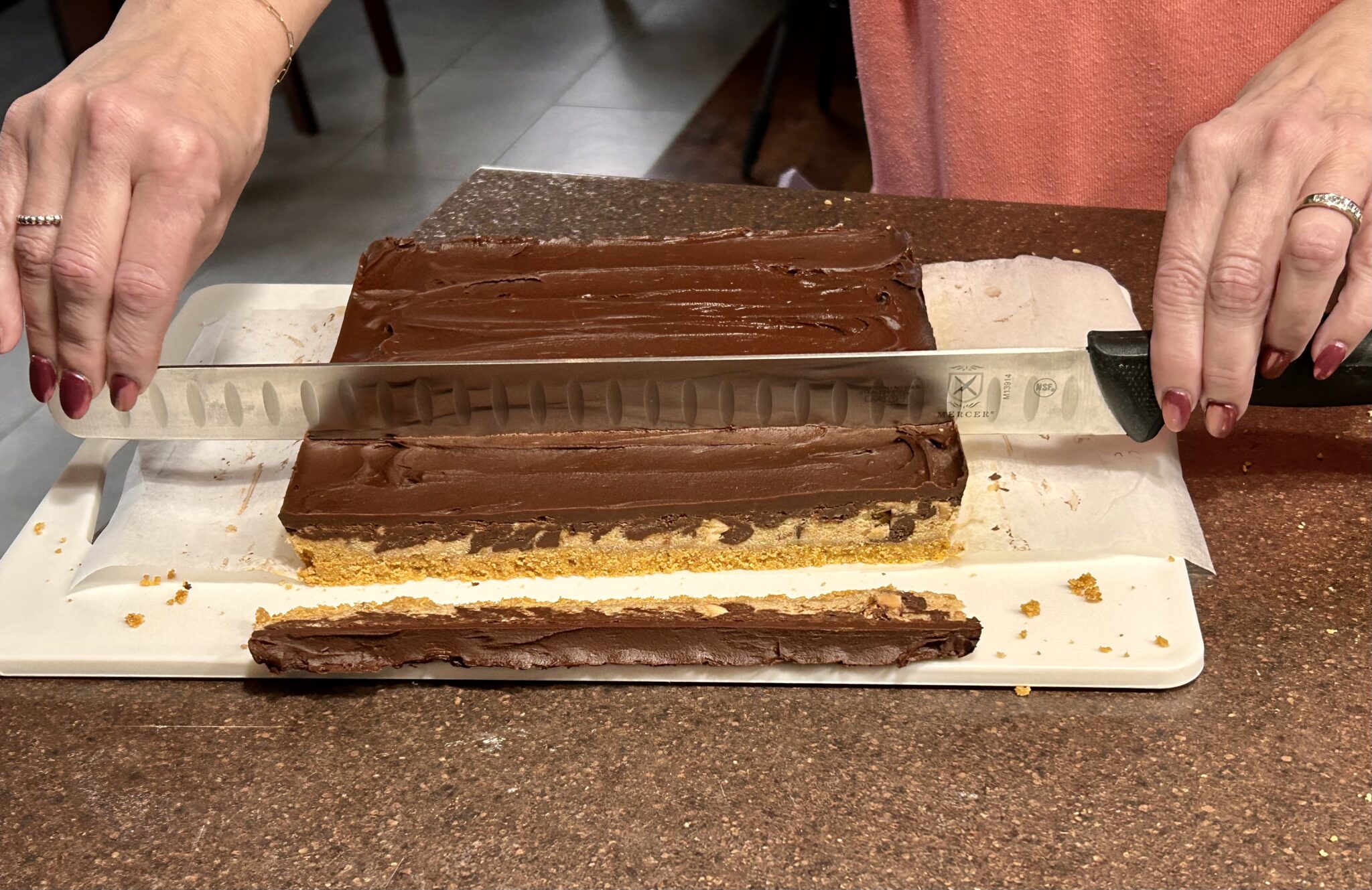 Photo of cookie bars being cut with a 14 inch blade knif.