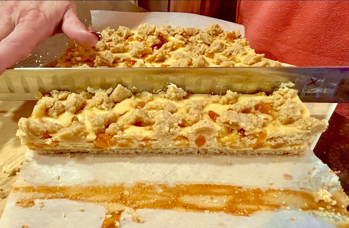 Photo of Apricot Amaretto Cheesecake Bars being cut with a 14 inch slicing knife.