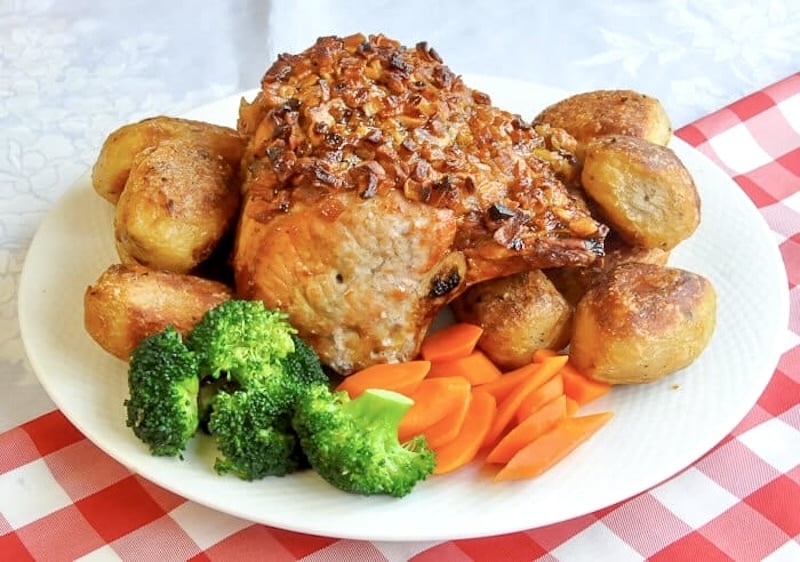 Apple Roasted Pork photo of uncut roast on a platter with vegetables
