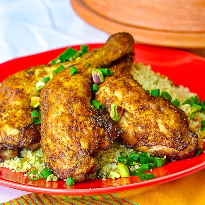 Baked Moroccan Chicken with Pistachio Lemon Couscous shown on a red serving platter