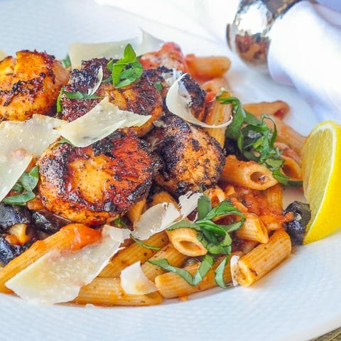 Cajun Scallops Puttanesca close up photo of a single serving on a white plate