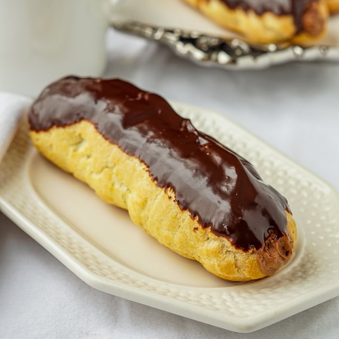 Chocolate Mousse Eclairs photo of a single uncut eclair on a white plate