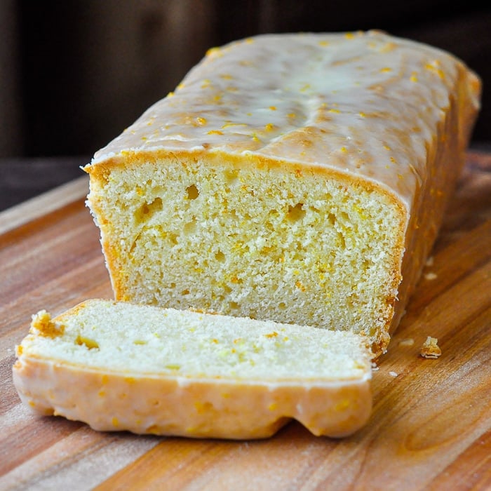 Glazed Orange Pound Cake on a wooden cutting board with one slice cut off