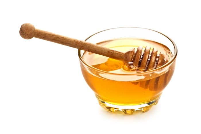 Honey in a glass pot with a solid white background.