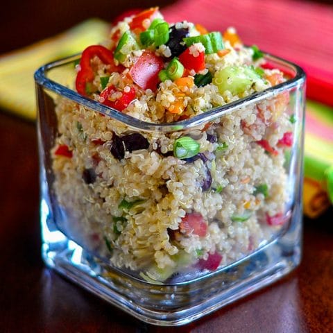 Mediterranean Quinoa Salad in a clear glass serving dish on a wooden table