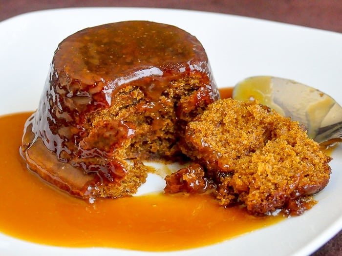 Perfect Sticky Toffee Pudding wide shot photo of singoe serving on a white plate