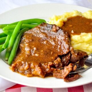 Photo of one serving of stewed steak shown with mashed potatoes and green beans