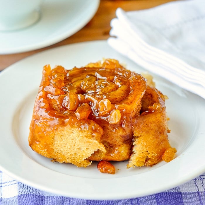 Rum Raisin Sticky Buns close up image on white plate with napkin and coffee cup