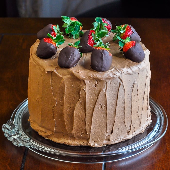 Too Tall Neapolitan Cake photo of entire uncut cake topped with a ring of chocolate dipped strawberries