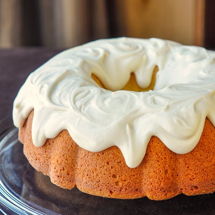 Vanilla Cream Cheese Bundt Cake photo of uncut cake on a clear glass serving plate