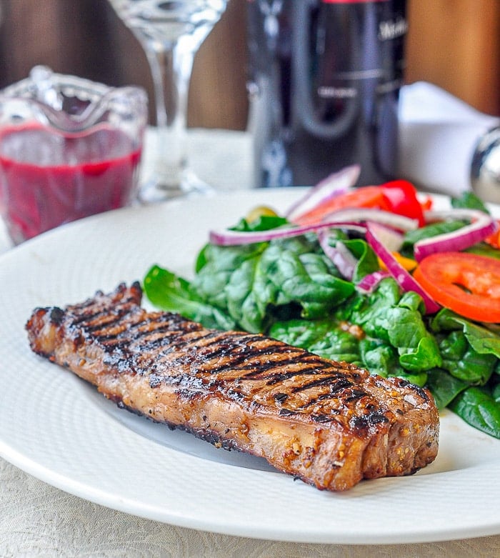 Dijon Balsamic Marinated Steak shown on a white plate with salad