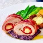 Prosciutto Wrapped Chicken Breasts on a white plate with green beans, tapinade and potatoes
