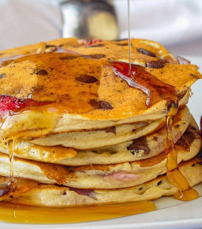 Strawberry Chocolate Chip Buttermilk Pancakes close up photo of maple syrup being poured onto pancakes