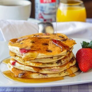 Strawberry Chocolate Chip Buttermilk Pancakes on a white plate with coffee and orange juice in background