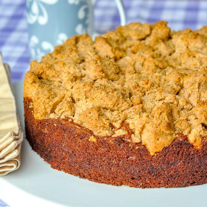 Walnut Crumble Banana Coffee Cake photo of uncut cake on white serving plate