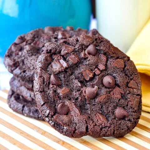 photo of Double Chocolate Mint Chip Cookies on a bamboo cutting bard with milk in background