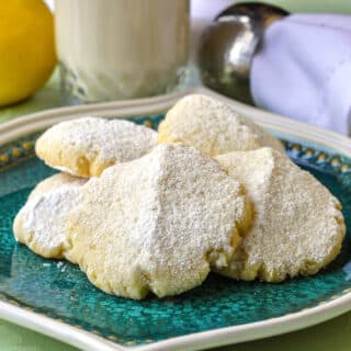Lemon Snow Cookies shown with a glass of milk in the background
