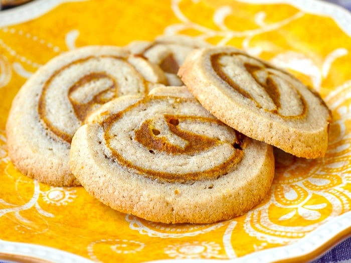 Pumpkin Pie Pinwheel Cookies stacked on a yellow patterned plate