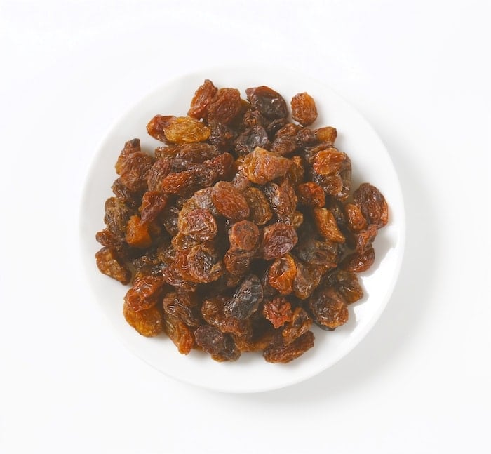 Raisins for Hot Cross Buns shown in a white bowl.