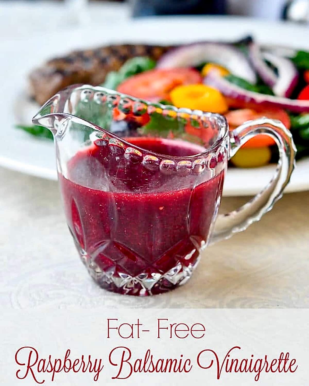 Raspberry Balsamic Vinaigrette photo of dressing in a clear glass crystal jug with title text added for Pinterest and social media posts.
