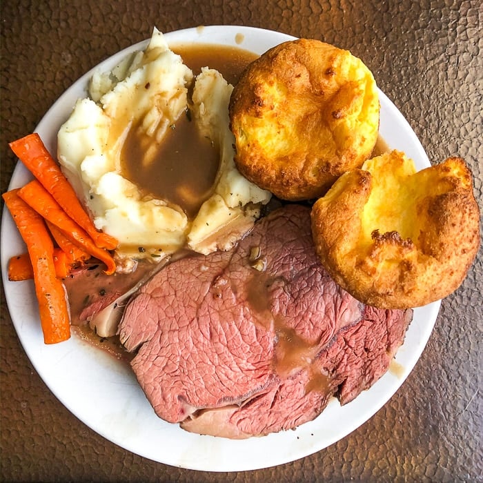 Herb and Garlic Crusted Prime Rib Roast plated with mashed potatoes, gravy, roasted carrots and yorkshire pudding.