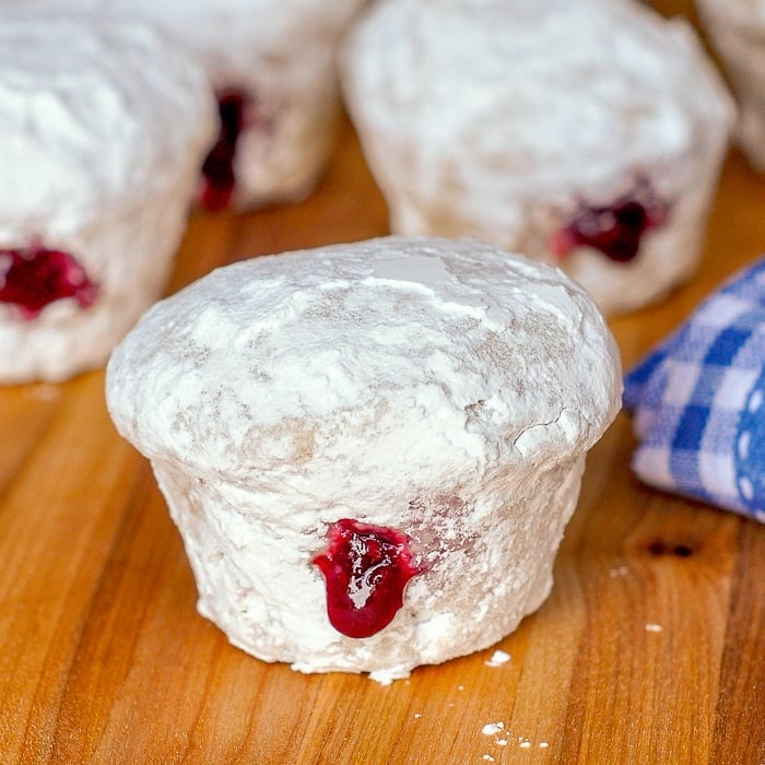 Raspberry Filled Donut Muffins close up photo of a muffin on a wooden cutting board