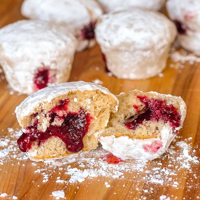 Raspberry Filled Donut Muffins shown on a dark brown wooden cutting board