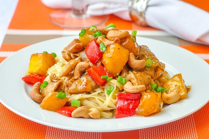 Spicy Mango Orange Pork with Cashews wide shot of a single serving on a white plate