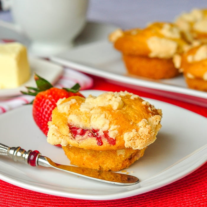 Strawberry Muffins with Shortbread Crumble photo of a single muffin with coffee and more muffins in the background