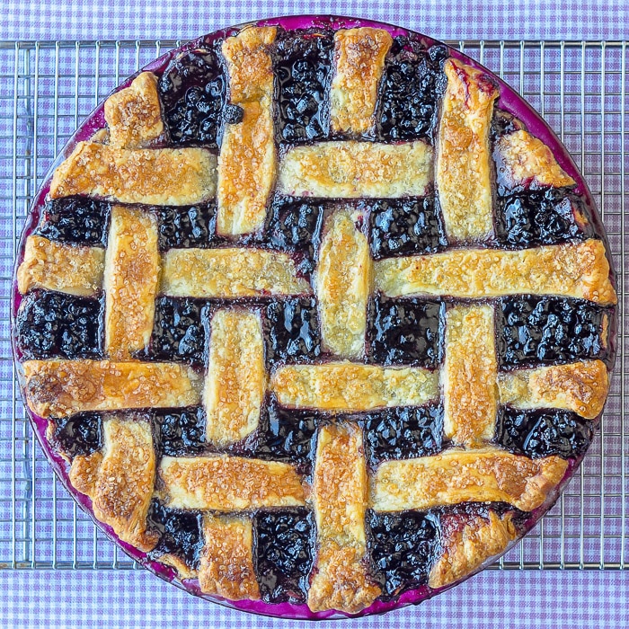 The Best Blueberry Pie, overhead photo of entire pie on a blue checkered background