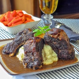 St. John's Stout Braised Beef Ribs on brown rimmed plate with gravy and mashed potatoes.