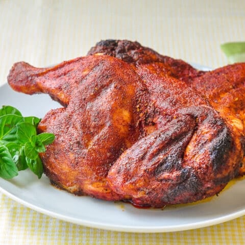Dry Rubbed Barbecue Chicken. with fresh herbs on a white plate