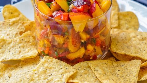 Peach Basil Salsa in a clear class serving dish with tortilla chips