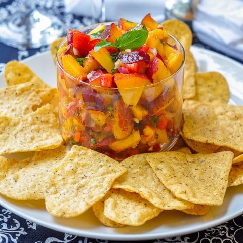 Peach Basil Salsa in a clear class serving dish with tortilla chips