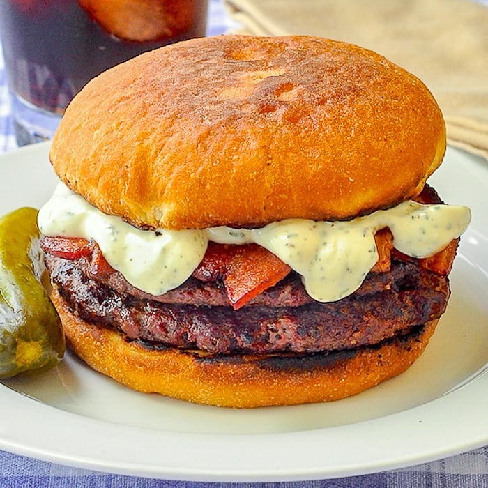 The Ultimate Newfie Touton Burger close up photo of burger on white plate with a dill pickle