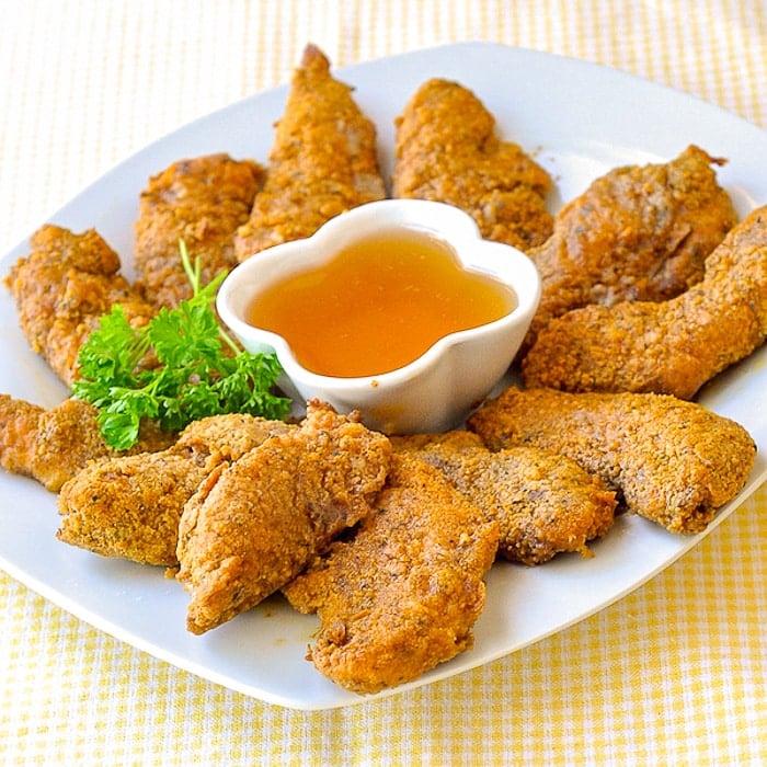 The Best Oven Fried Chicken Nuggets shown with honey dip on a white serving platter