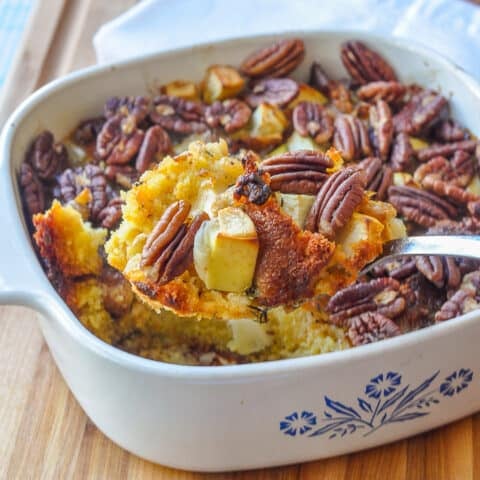 Apple Pecan Cornbread Stuffing close up photo of stuffing being served from a white Corningware casserole dish