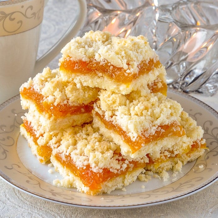 Apricot Coconut Crumble Bars on a serving plate with tea and votive candles in background