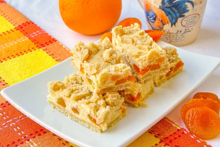 Apricot Orange Cheesecake Bars wide shot photo of the cookie bars stacked on a white platter