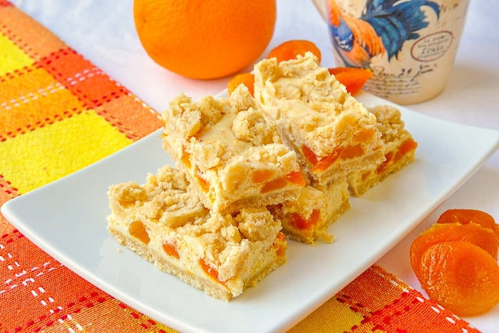 Apricot Orange Cheesecake Bars wide shot photo of the cookie bars stacked on a white platter