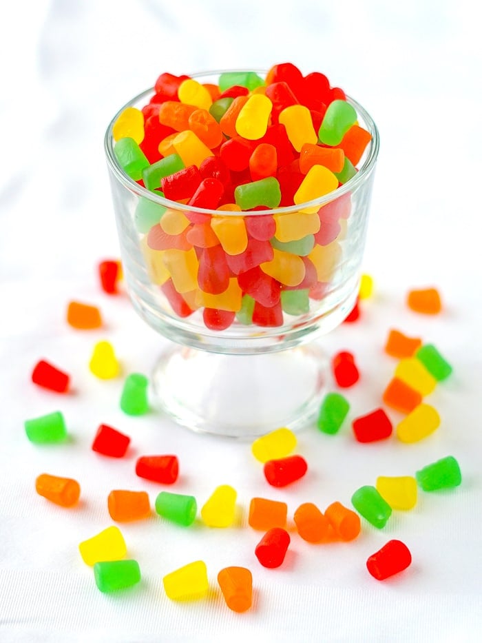 Baking gumdrops in a clear glass bowl with additional gumdrops strewn around it.
