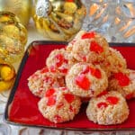 Easy Cherry Almond Macaroons shown on red serving plate with Christmas decorations in background