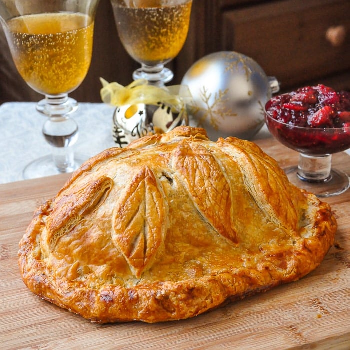 Cranberry Hazelnut Turkey Wellington shown uncut on a wooden cutting board