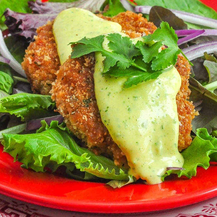 Shrimp Cakes with lime aioli photo close up photo of 2 shrimp cakes on a bed of greens
