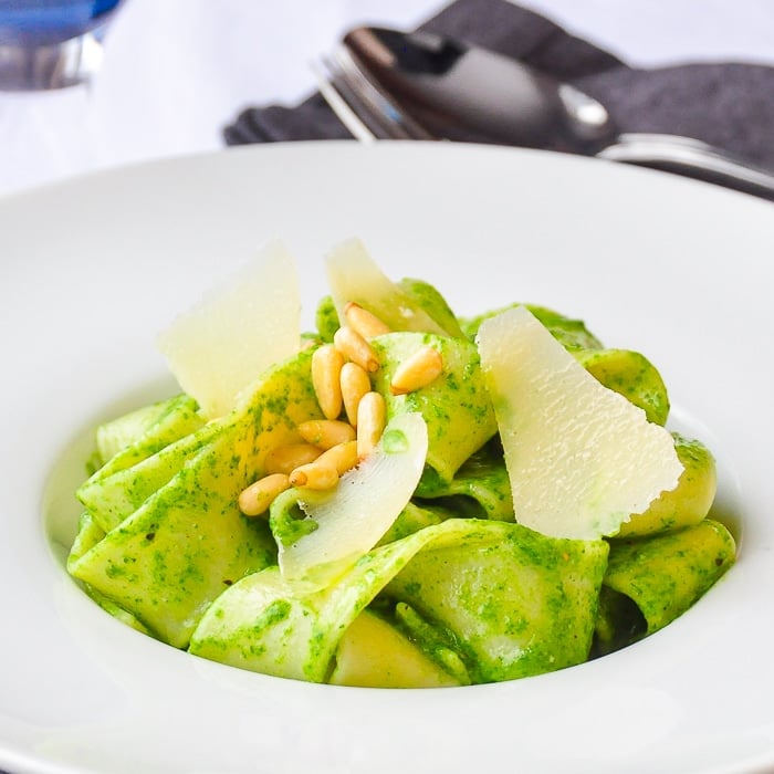 Close up photo of Spinach Pesto Pappardelle with parmesan shavings and pine nuts as garnish