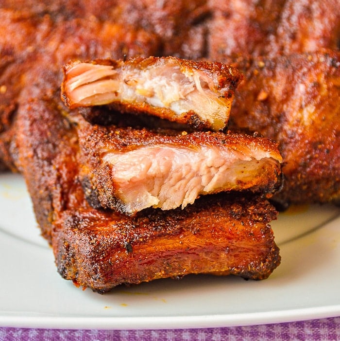 Dry Rubbed Oven Ribs stacked on a white plate